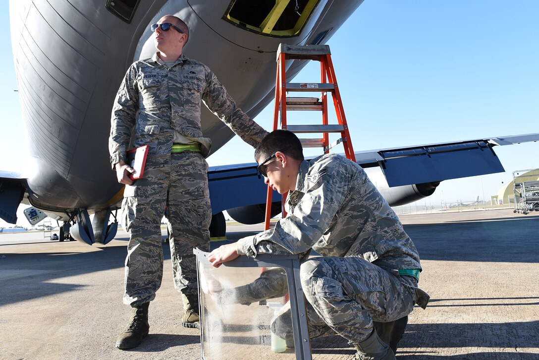 Two Airmen fix a jet window.