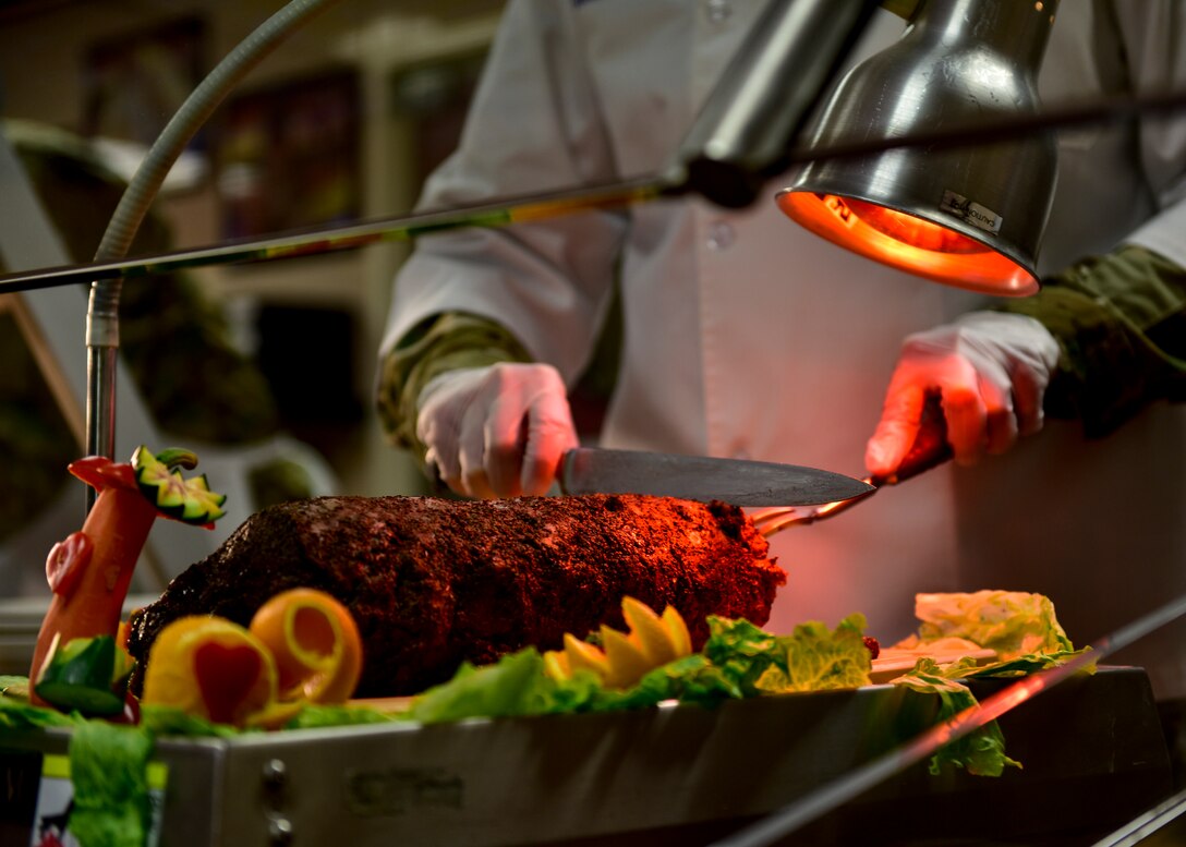 Col. Richard Gibbs, 377th Air Base Wing commander, cuts prime rib for the annual Thanksgiving meal at Thunderbird Inn, Nov. 22, 2018. Various commanders and command chiefs took turns serving Thanksgiving meals to Airmen and their families throughout the holiday. (U.S. Air Force Photo by Airman 1st Class Austin J. Prisbrey)