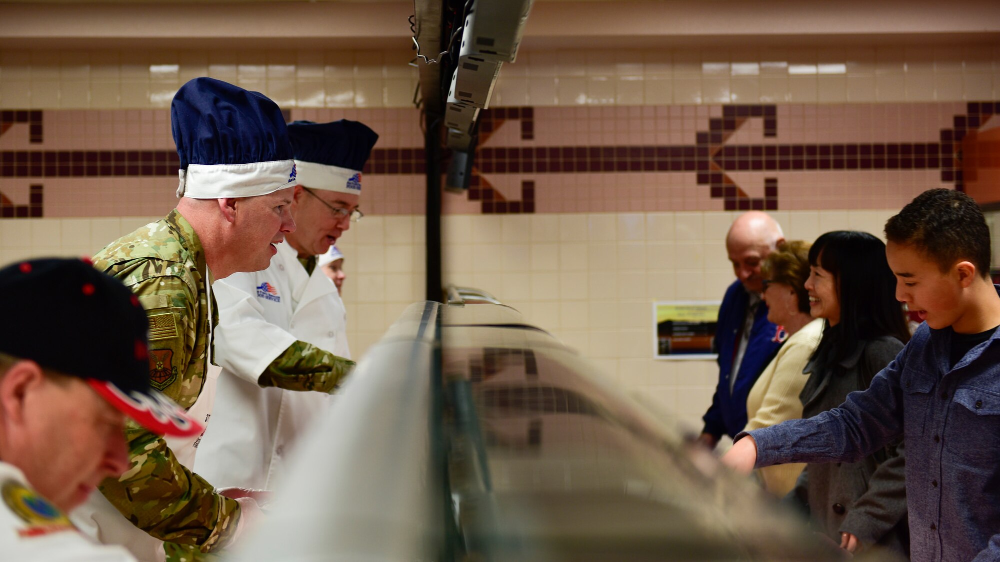 Chief Master Sgt. Robert Stamper, 377th Air Base Wing command chief and Col. Richard Gibbs 377th Air Base Wing commander, serve food for Thanksgiving at Kirtland, Nov. 22, 2018. The spouses of the commanders and command chiefs also helped serve food throughout the holiday. (U.S. Air Force Photo by Airman 1st Class Austin J. Prisbrey)