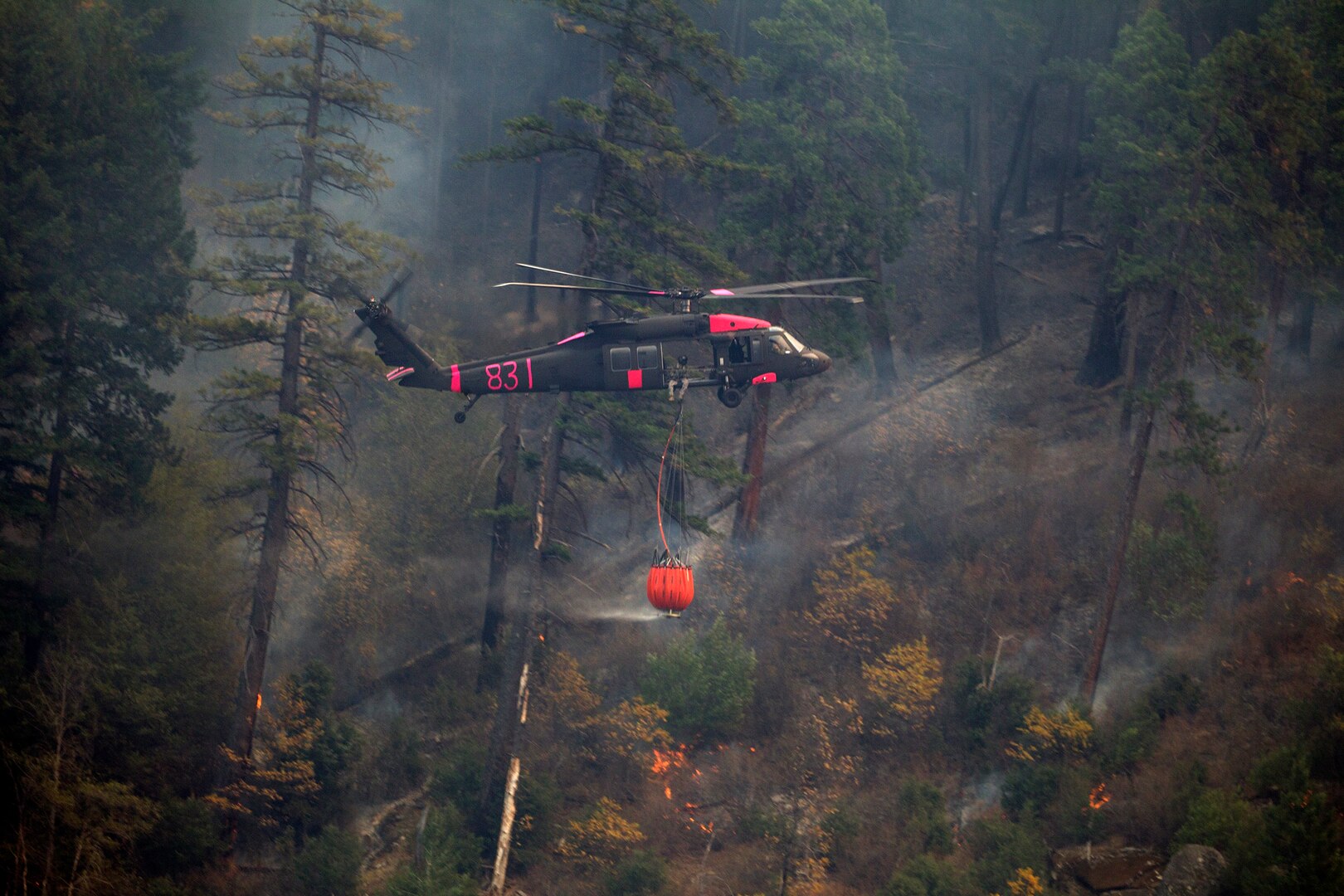 A U.S. Army UH-60M Black Hawk helicopter co-piloted by 1st Lt. Vincent Sherrill of the California Army National Guard's 1st Assault Helicopter Battalion, 140th Aviation Regiment, flies through the Feather River Canyon with a bucket of water, Nov. 16, 2018, in Butte County, California, during a mission to drop water on the deadly Camp Fire.