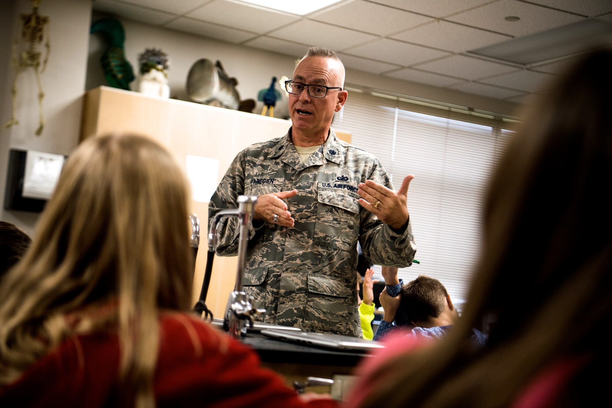 Sharing time with middle school students, Lt. Col. Stan Paregien, 932nd Airlift Wing Chief of Public Affairs, speaks to the Highland Junior High regarding the mission of the 932nd Airlift Wing, patriotism, airplanes, and remembering other veterans. He set up a 932nd AW display booth and answered questions about the Air Force Reserve, as eighth grade students rotated through every hour.  He handed out military gear for students to pass around, along with an American flag, and answered student's questions about what it takes to become an American Airman during an all day Veterans event held Nov. 9, 2018.  Other unit members attending were Master Sgt. Chris Parr and Lt. Col. Brandon Lorton.  (U.S. Air Force photo by Master Sgt. Chris Parr)