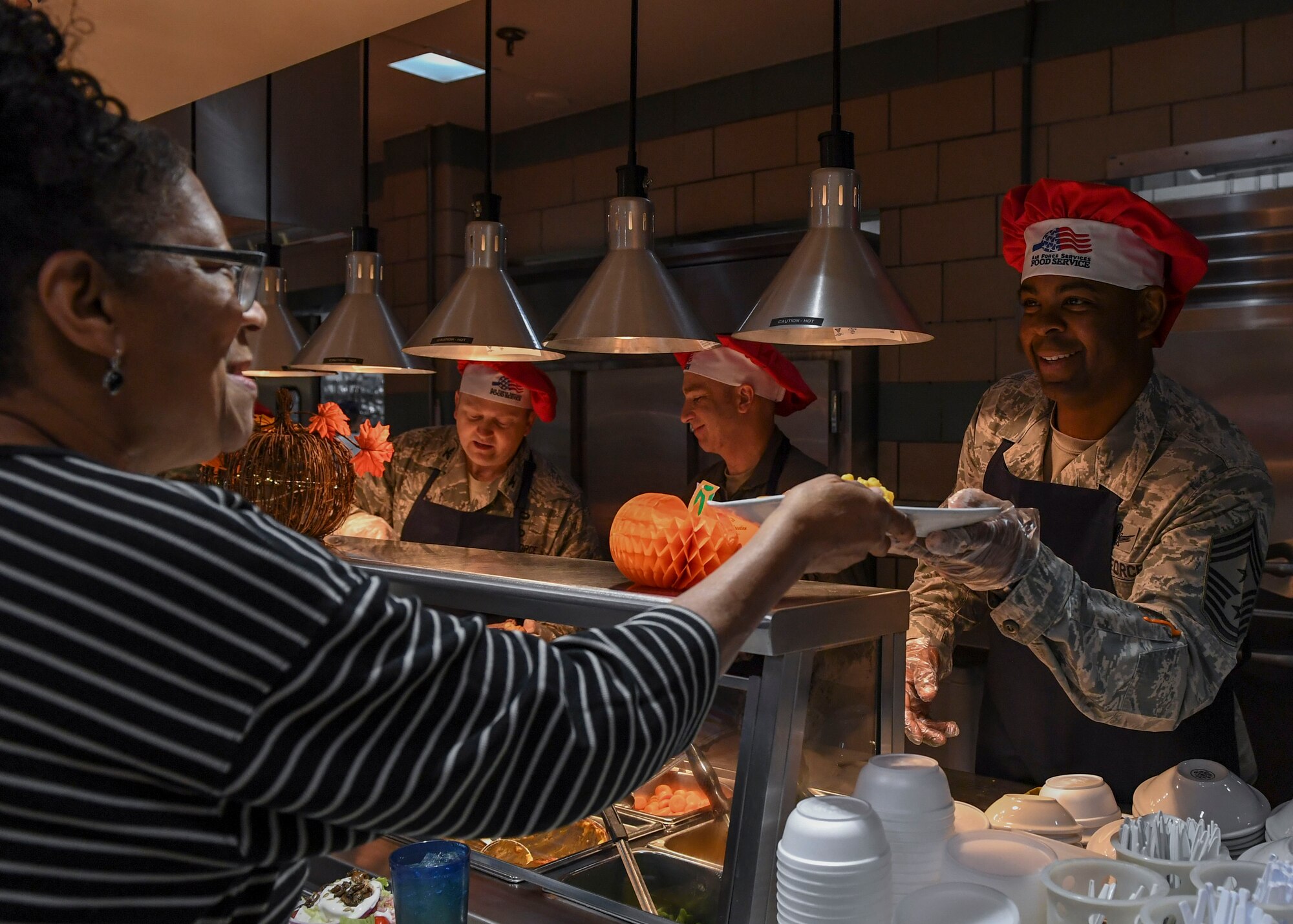 U.S. Air Force Chief Master Sgt. Jay Harris, 1st Fighter Wing command chief, hands a Thanksgiving meal to a Crossbow Dining Facility patron at Joint Base Langley-Eustis, Virginia, Nov. 22, 2018.
