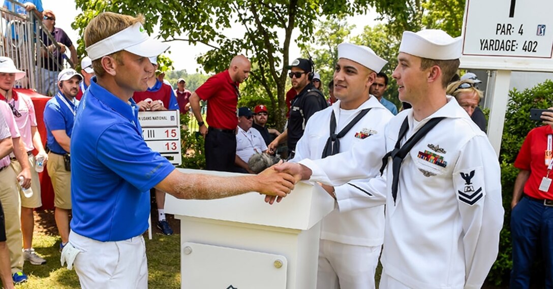 Golfer Billy Hurley III shakes hands with sailors on golf course.