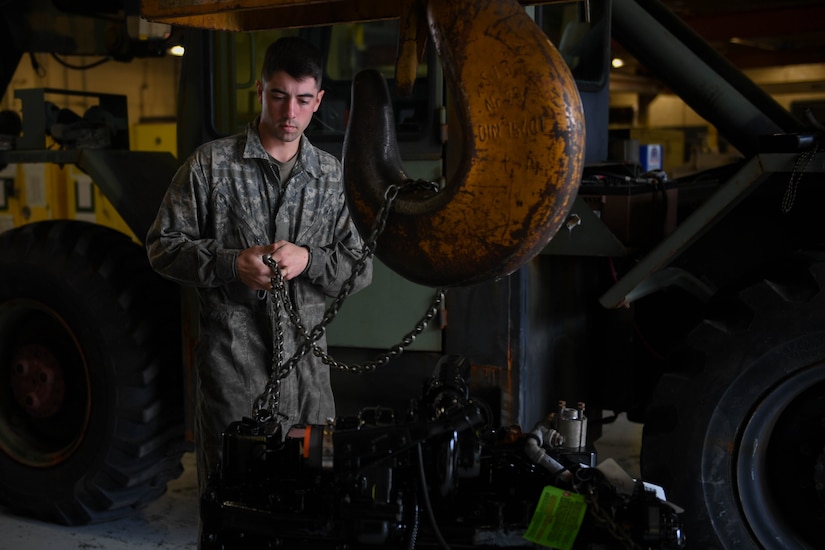 U.S. Army Spc. Lathan Griener, 149th Seaport Operations Company, 10th Transportation Battalion, 7th Trans. Brigade (Expeditionary) welder, secures an engine to a crane hook at Joint Base Langley-Eustis, Virginia, Nov. 19, 2018. Griener was tasked to prepare a new engine for installment when the necessary parts arrived to the motor pool. (U.S. Air Force photo by Senior Airman Derek Seifert)