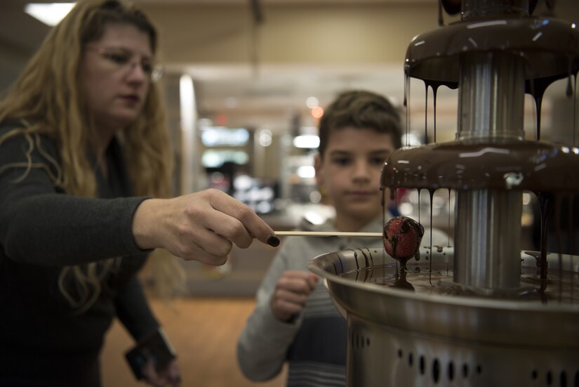 Community members dip a strawberries into a chocolate fountain during a Thanksgiving dinner on Joint Base McGuire-Dix-Lakehurst, New Jersey, Nov. 22, 2018. The dinner offered meals to service members and their families and was served by leadership from multiple units. (U.S. Air Force photo by Airman 1st Class Ariel Owings)
