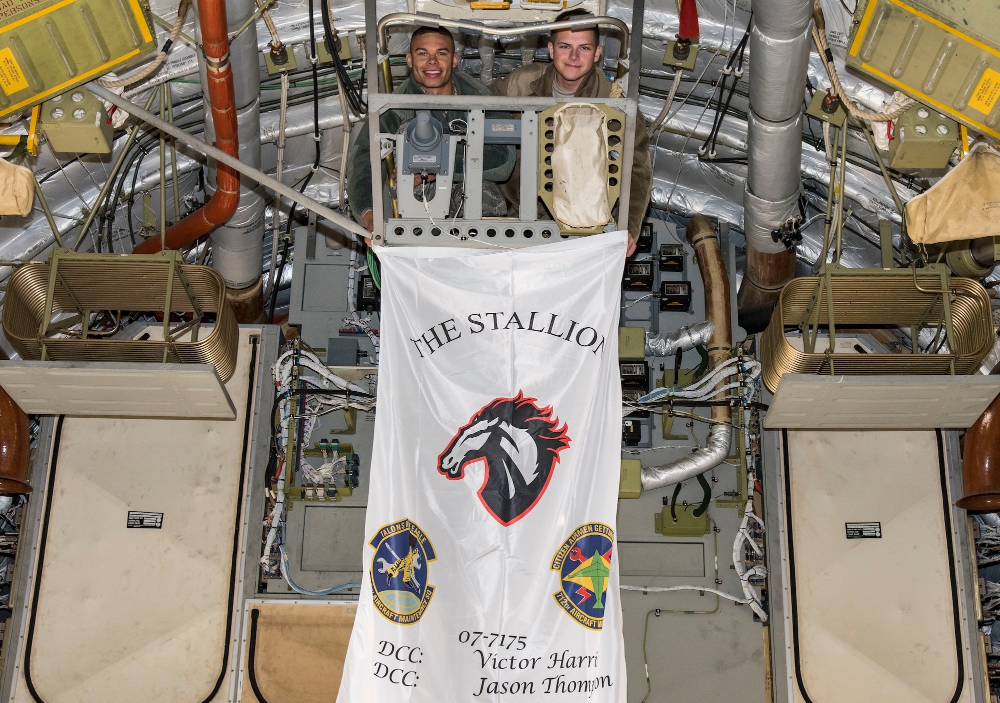 Senior Airman Victor Harris, right, Dedicated Crew Chief, and Airman 1st Class Jason Thompson, left, Assistant DCC, both assigned to the 736th Aircraft Maintenance Squadron, hold their aircraft flag where it will hang Nov. 21, 2018, at Dover Air Force Base, Del. Each of the 13 C-17 Globemaster III aircraft assigned to Dover will display a flag showing the unofficial name of the aircraft, tail number, and the names of the DCC and ADCC. (U.S. Air Force photo by Roland Balik)
