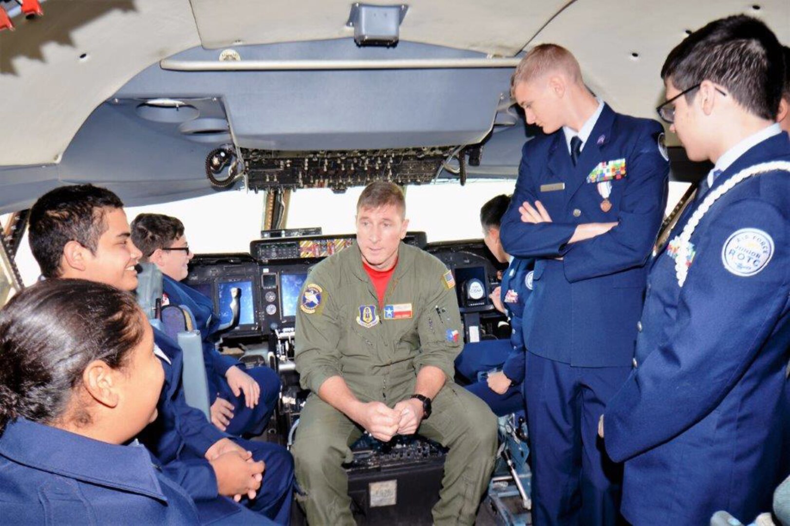 Flight Engineer Tech. Sgt. Ryan Lohrer with the 68th Airlift Squadron, Joint Base San Antonio-Lackland, seated center in the new upgraded C-5M Super Galaxy, Nov. 16, 2018, explains the different controls located in the cockpit to Porter High School Air Force Junior Reserve Officers’ Training Corps cadets.