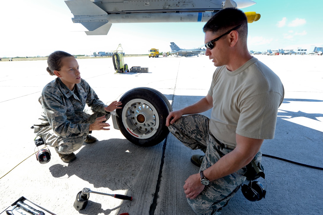 A picture of U.S. Air Force 2d Lt. Gabrielle Riley, equipment maintenance operations officer, and Senior Master Sgt. Michael Ferrari, aircraft mechanic supervisor, talking under the wing of a U.S. Air Force F-16C Fighting Falcon.