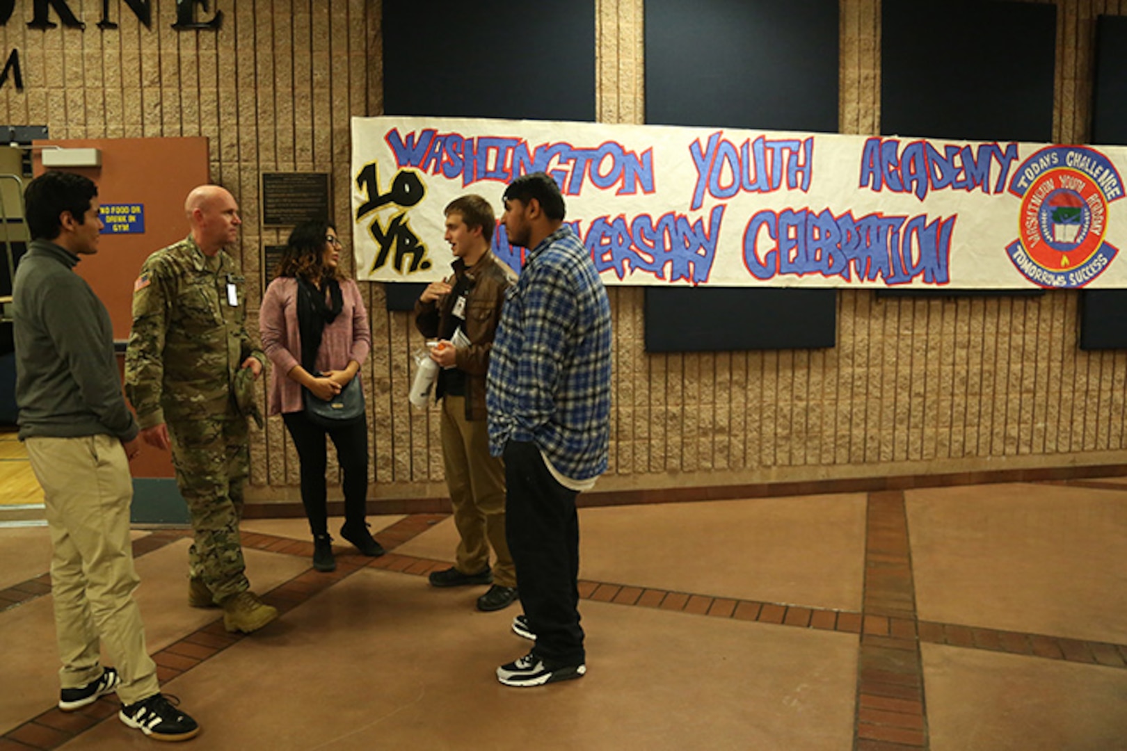 Washington Youth Academy 1st Lt. Darrell Stoops talks with former graduates of the WYA during the academies 10-year anniversary ceremony Nov. 18, 2018, in Bremerton, Wash. The ceremony brought together former and current graduates as a way to reconnect with past graduates, as well as show the current class the success the program can lead to.