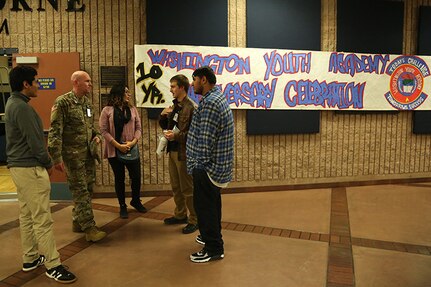 Washington Youth Academy 1st Lt. Darrell Stoops talks with former graduates of the WYA during the academies 10-year anniversary ceremony Nov. 18, 2018, in Bremerton, Wash. The ceremony brought together former and current graduates as a way to reconnect with past graduates, as well as show the current class the success the program can lead to.