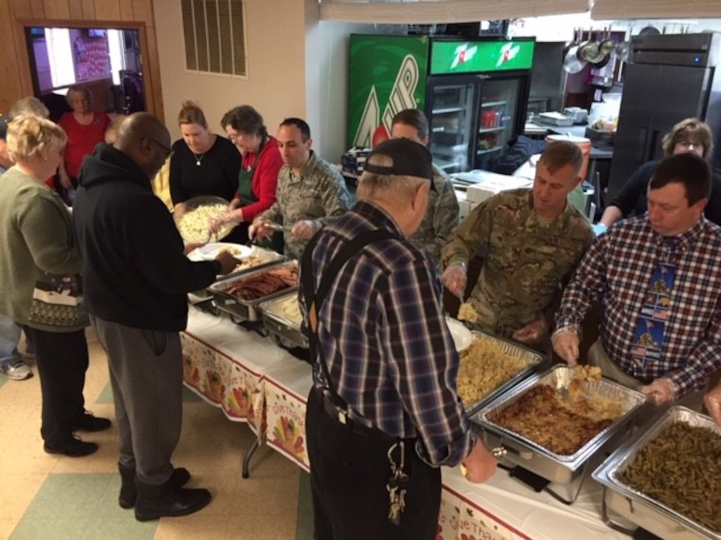 Members of the military and civilian volunteers serve Thanksgiving dinner to veterans as they walk down the buffet line