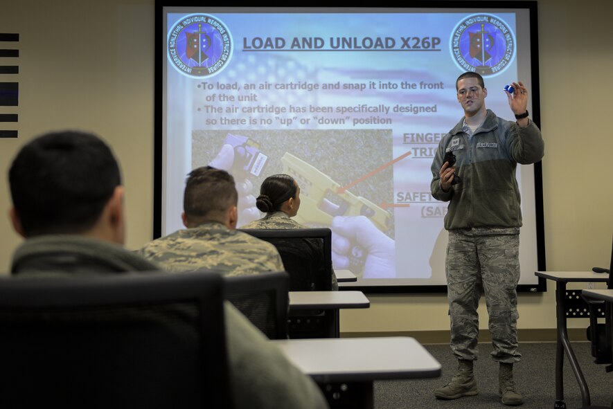 Staff Sgt. Corey Ormsby, 375th Security Forces Squadron training instructor, explains the loading and unloading procedures of an X26P taser prior to hands on baton and taser training at Scott Air Force Base, Illinois, Nov. 19, 2018. Each security forces member receives classroom and practical application training on the taser before being certified to carry it for duty use.  (U.S. Air Force photo by Senior Airman Daniel Garcia)