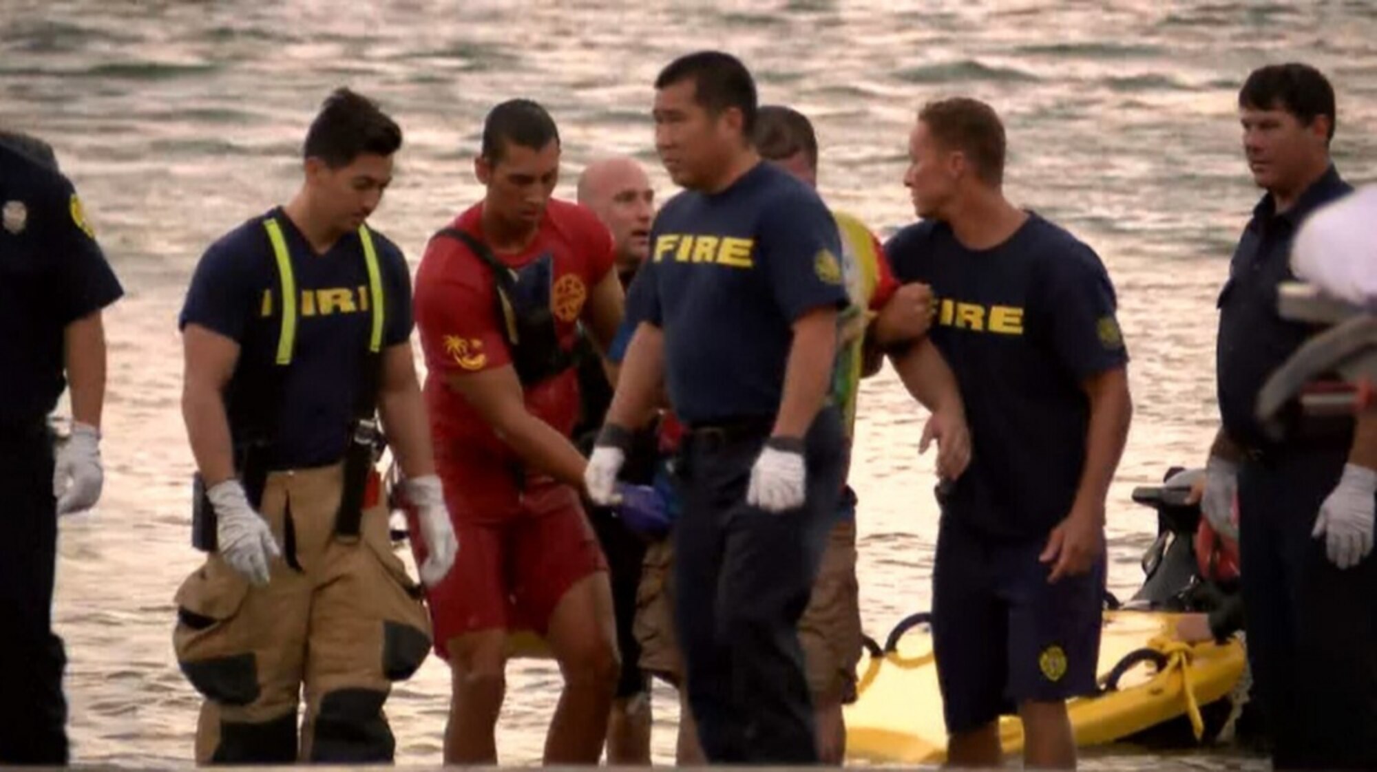 Senior Airman Casey Whitworth (red), a full-time lifeguard and triage response team member of the Hawaii Air National Guard, delivers a victim of a helicopter crash to the care of firefighters and emergency medical services October 22, at Kaneohe Bay, Hawaii.