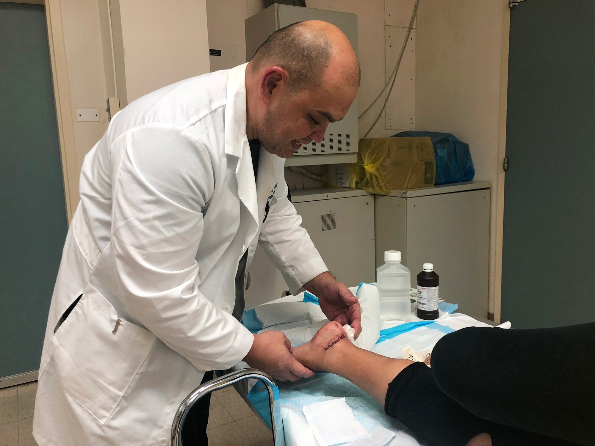 Dr. John Tudela, center, the chief medical officer at the Commonwealth Health Center, inspects a patients sutures in the emergency room Oct. 25, 2018, at CHC as part of the medical response during Super Typhoon Yutu in Saipan, Northern Mariana Islands.