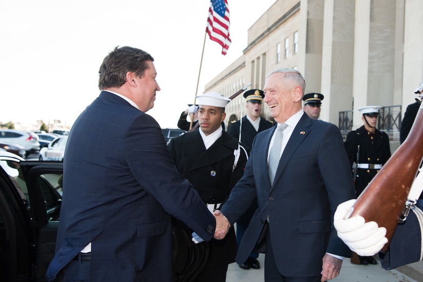 The U.S. secretary of defense shakes hands with the Lithuanian minister of defense during a ceremony