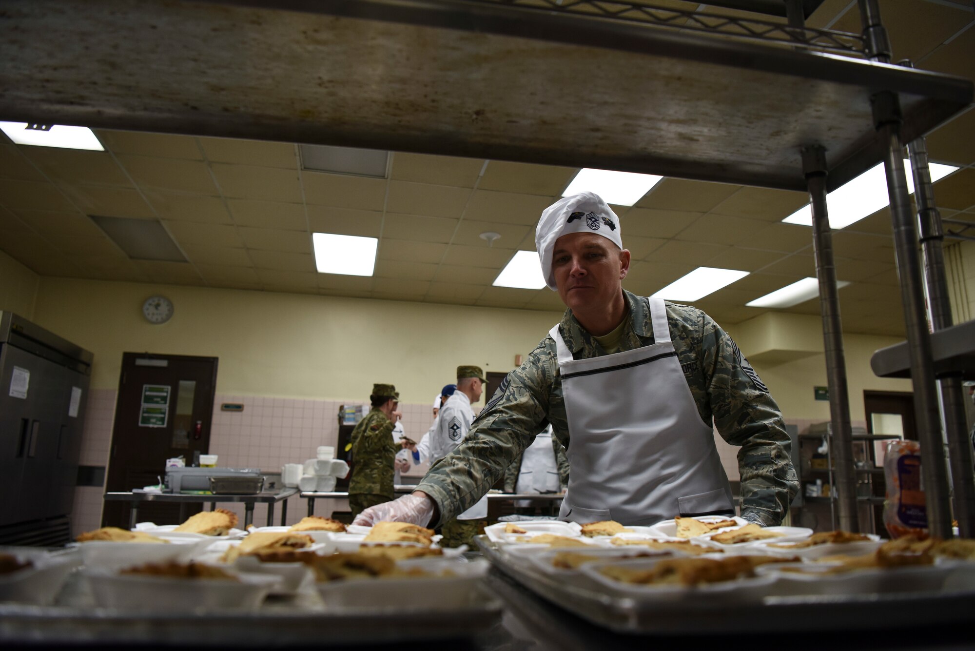 U.S. Air Force Chief Master Sgt. Michael Moore, 8th Fighter Wing command chief, sets down a tray of pumpkin pie at Kunsan Air Base, Republic of Korea, Nov. 22, 2018. Seventh Air Force leadership joined base leadership as they prepared and served a Thanksgiving meal to Airmen. (U.S. Air Force photo by Senior Airman Savannah L. Waters)