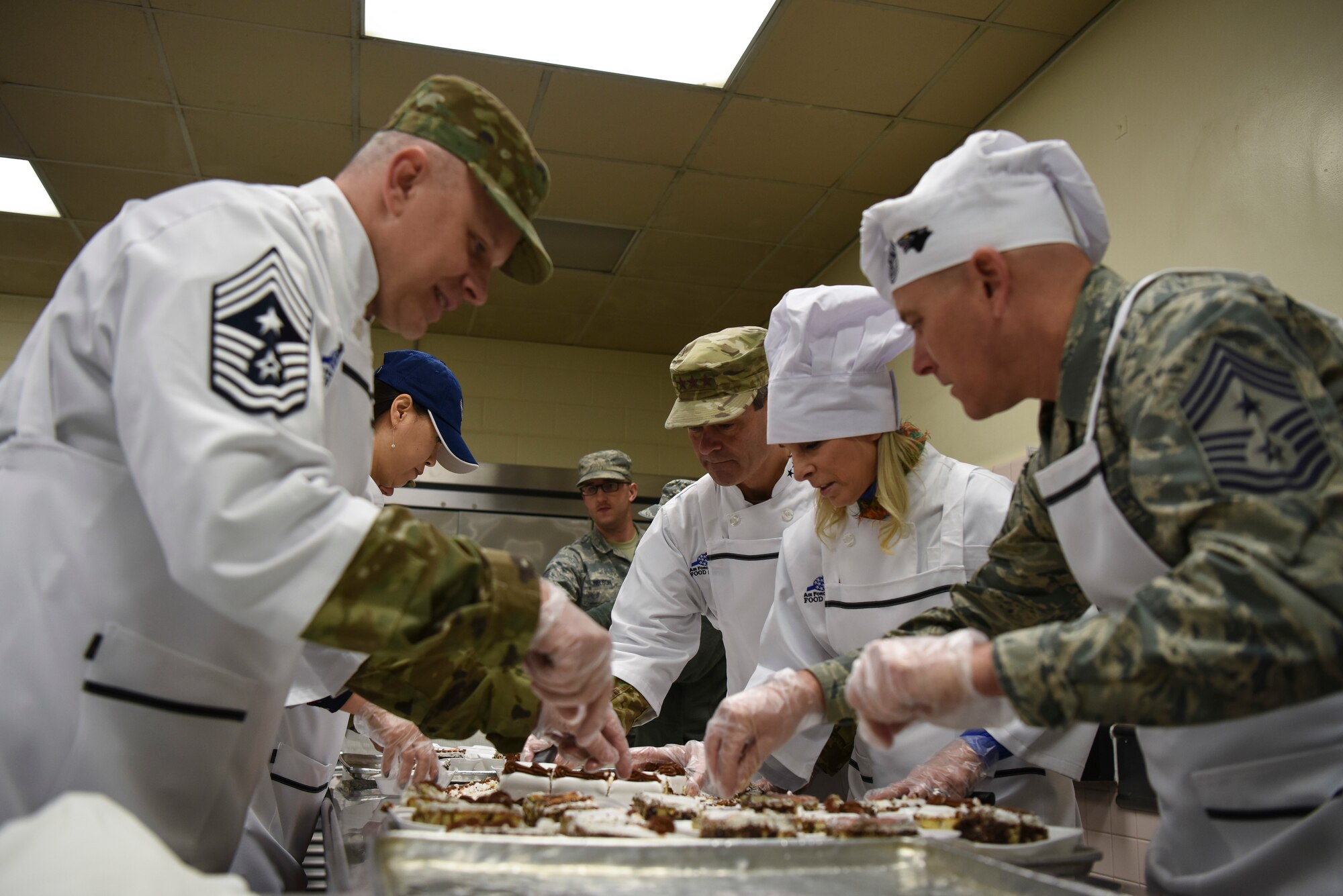 Leadership from both the 8th Fighter Wing and Seventh Air Force cut cake at Kunsan Air Base, Republic of Korea, Nov. 22, 2018. Gen. Wilsbach, his wife, Cynthia, and other Seventh Air Force leadership joined base leadership as they prepared and served a Thanksgiving meal to Airmen. (U.S. Air Force photo by Senior Airman Savannah L. Waters)