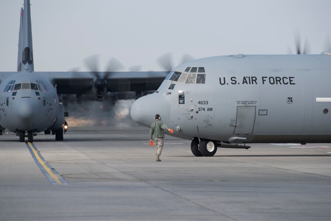 A crew chief, assigned to the 374th Aircraft Maintenance Squadron, marshals a C-130J Super Hercules during the 374th Airlift Wing Samurai Surge at Yokota Air Base, Japan, Nov. 29, 2018.