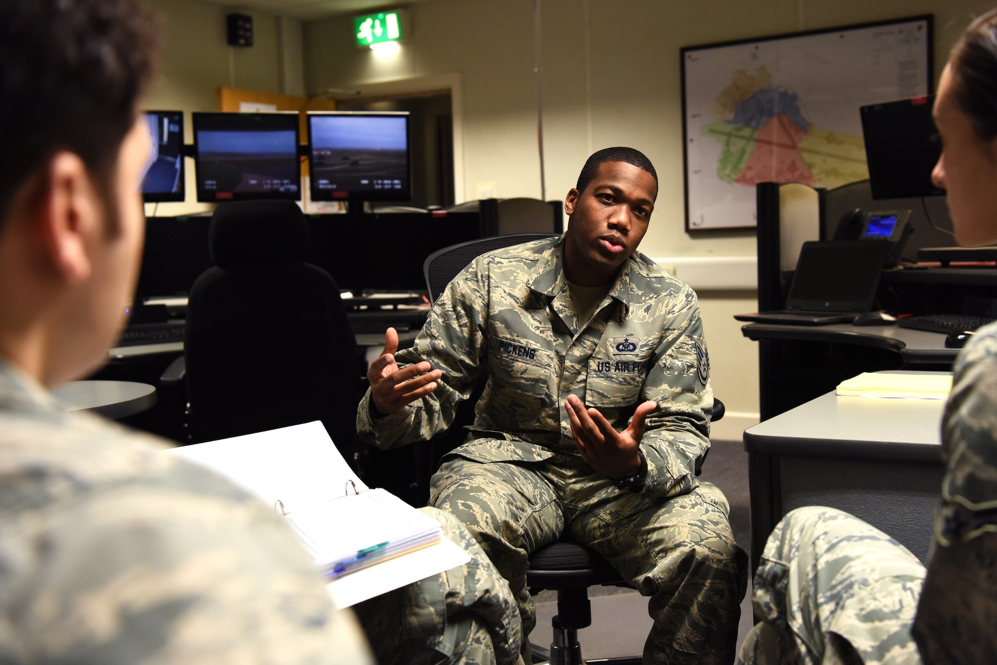U.S. Air Force Staff Sgt. Justin Pickens, 100th Air Refueling Wing Command Post NCO-in-charge of command and control training, discusses operational checklists with new Airmen in the command post at RAF Mildenhall, England, Nov. 27, 2018. The command post serves as the nerve center from which base leadership monitor and manage the readiness and response of various wings. (U.S. Air Force photo by Airman 1st Class Brandon Esau)
