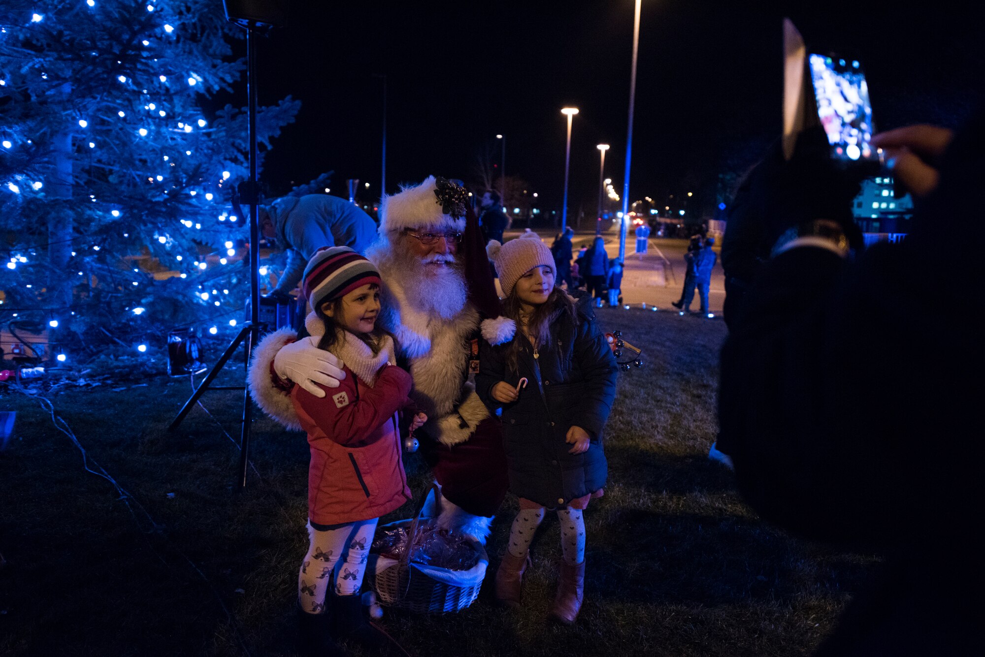Santa Claus takes a photo with children on Ramstein Air Base, Germany, Nov. 27, 2018. Claus made his appearance after the tree lighting ceremony ended. (U.S. Air Force photo by Senior Airman Devin M. Rumbaugh)