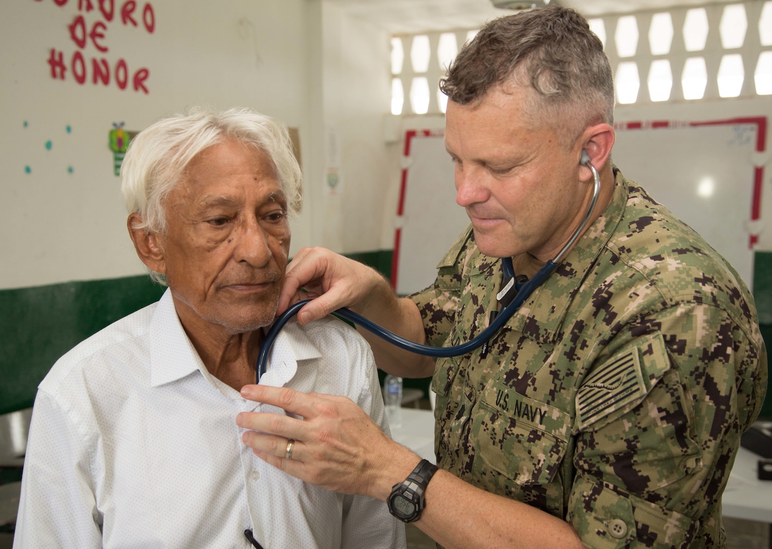 Cmdr. Ryan Griswold, from Madison, Iowa, examines a patient for health issues at one of two medical sites.