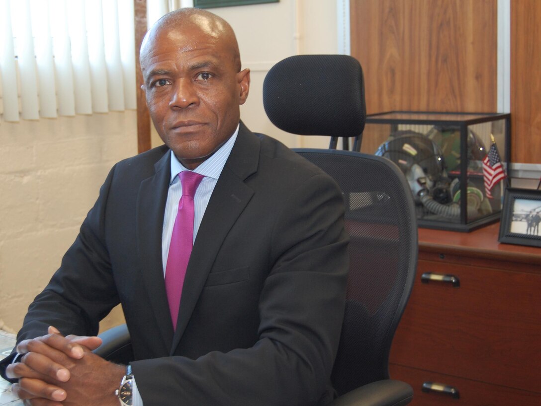 Photo of a man in a suit sitting in a chair at his desk