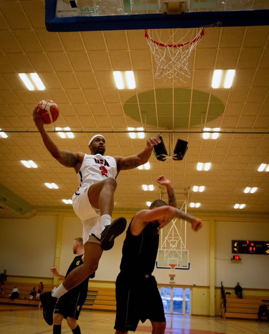 United States Armed Forces Basketball Team member Derell Henderson shoots over Belgian Team’s defense in the first game of the 2018 SHAPE International Basketball Tournament, Belgium, November 26, 2018. The annual event brings together teams from around the world for friendly competition and partnership at a prominent NATO installation.(U.S. Air Force photo by Broadcast Journalist Senior Airman Hannah Malone) — at Shape Sports & Fitness Centre.