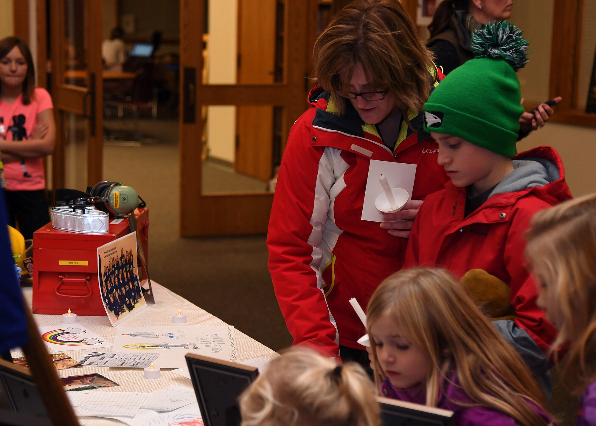 Families who attended a candlelight vigil for the Dean family stop to view a memorial table November 28, 2018, in St. Timothy’s Catholic Church, in Manvel, North Dakota. Staff Sgt. Anthony James Dean, his wife Chelsi Kay Dean, and their two children Kaytlin Merie Dean, 5, and Avri James Dean, 1, were killed in a vehicle accident near Billings, Montana, during the Thanksgiving Holiday. (U.S. photo by Airman 1st Class Elora J. Martinez)