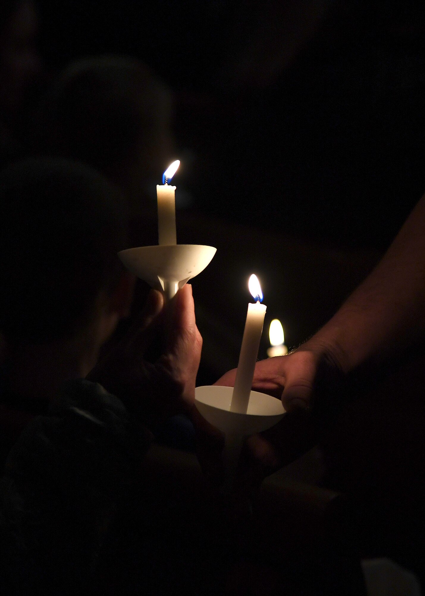 Members who attended a candlelight vigil in honor of the Dean family share a flame to light candles handed to all who joined the memorial November 28, 2018, in St. Timothy’s Catholic Church in Manvel, North Dakota. Staff Sgt. Anthony James Dean, his wife Chelsi Kay Dean, and their two children Kaytlin Merie Dean, 5, and Avri James Dean, 1, were all killed in a vehicle accident during the Thanksgiving holiday near Billings, Montana. Those who spoke at the memorial recalled fond memories of each family member, detailing how involved they were in the community. (U.S. Air Force photo by Airman 1st Class Elora J. Martinez)