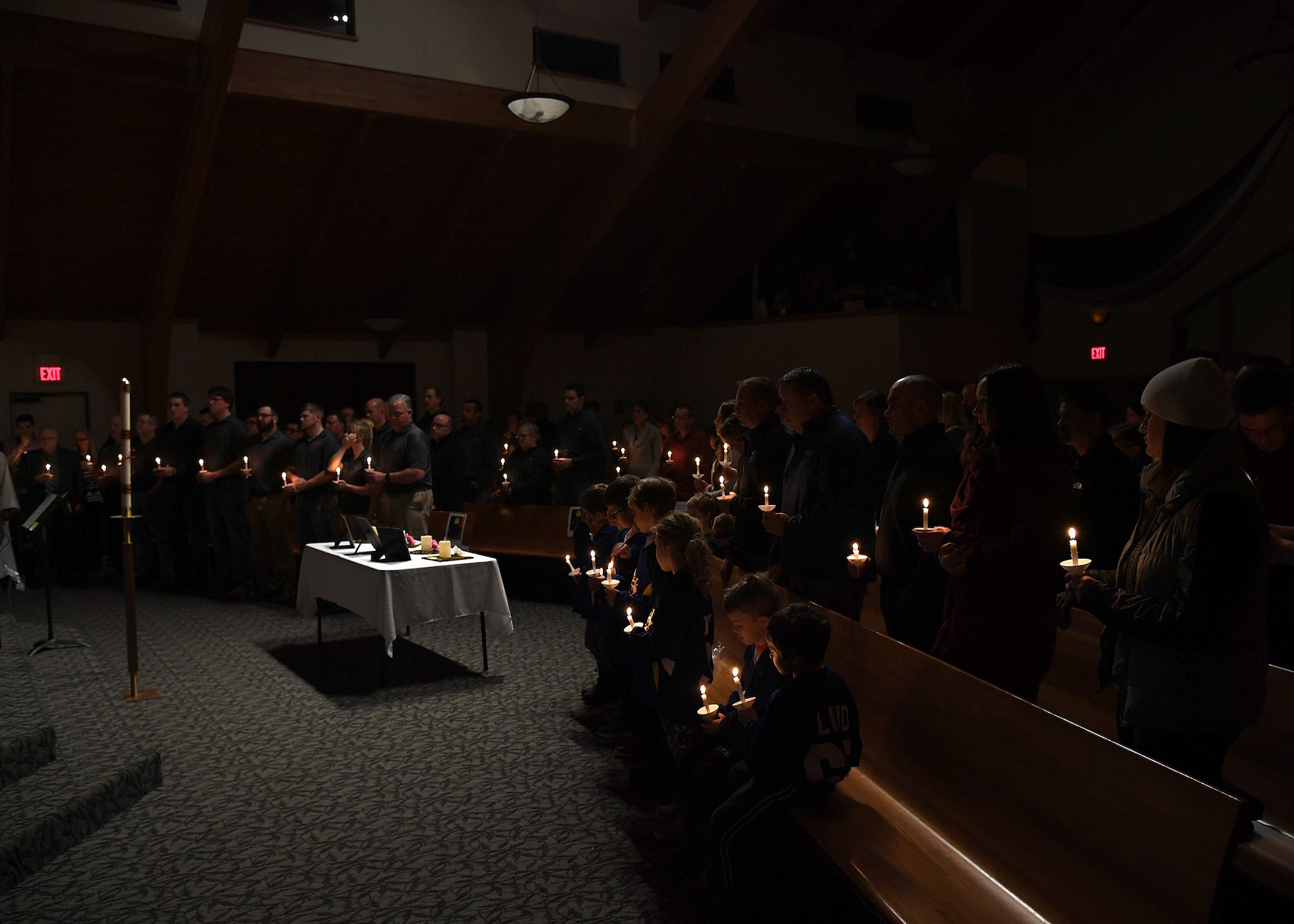 A crowd of nearly 100 people to include families, friends and coworkers from Grand Forks Air Force Base, the Manvel Fire Department and members of the local communities, stand in silence to honor the memories of the Dean family during a vigil hosted November 28, 2018, in St. Timothy’s Catholic Church, in Manvel, North Dakota. Staff Sgt. Anthony James Dean, his wife Chelsi Kay Dean, and their two children Kaytlin Merie Dean, 5, and Avri James Dean, 1, were all killed in a vehicle accident during the Thanksgiving holiday near Billings, Montana. The family was spoken of with love, and remembered by the stories shared of their significant involvement in the community. (U.S. photo by Airman 1st Class Elora J. Martinez)