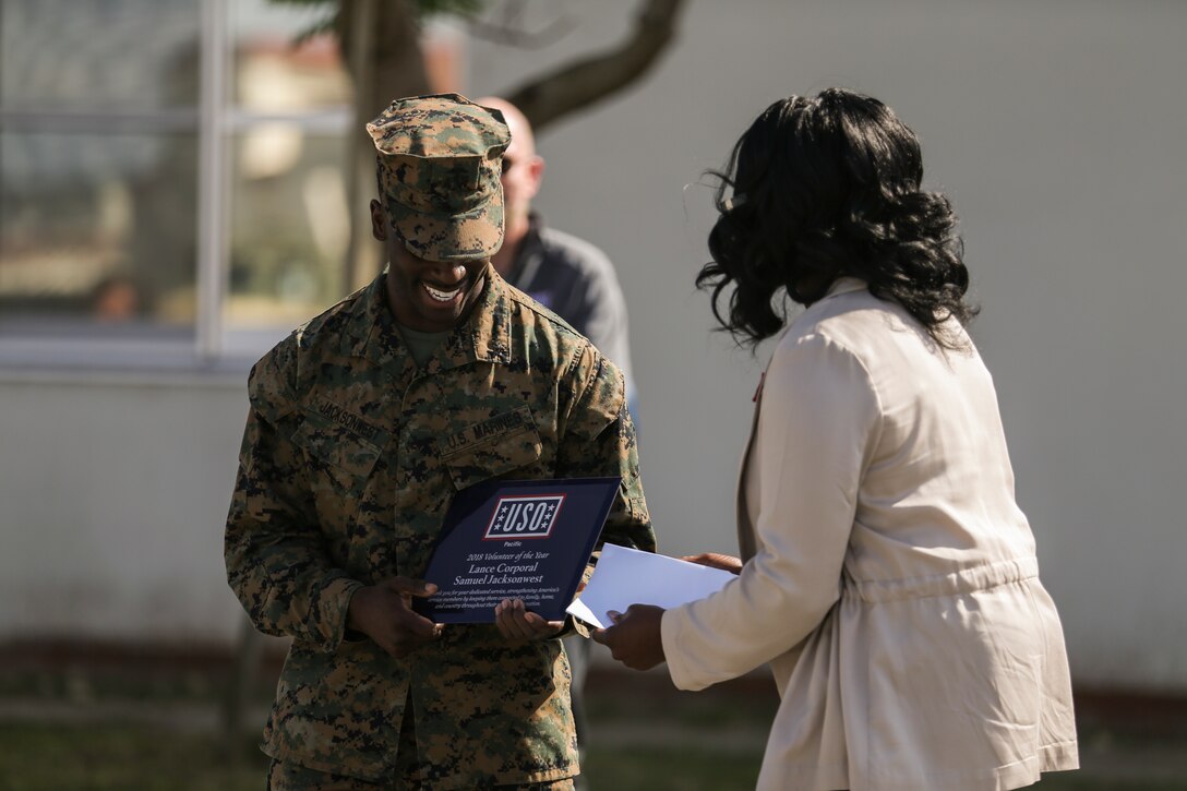 Tamara R. Owens, right, presents Lance Cpl. Samuel I. Jacksonwest, left, with the 2018 USO Pacific Volunteer of the Year award on Nov. 28, 2018 at Camp Foster, Okinawa, Japan. Jacksonwest received the award for his 480 volunteer hours at the Camp Foster USO. Jacksonwest was the winner among 1,400 volunteers in the Pacific region and the first active duty volunteer to receive this award in the last 4 years. Jacksonwest, a native of Atlanta, Georgia, is a network administrator with Headquarters Company, Combat Logistics Battalion 4, Combat Logistics Regiment 3, 3rd Marine Logistics Group. Owens, a native of Lima, Ohio, is the center manager of the Camp Foster USO. (U.S. Marine Corps photo by Lance Cpl. Armando Elizalde)