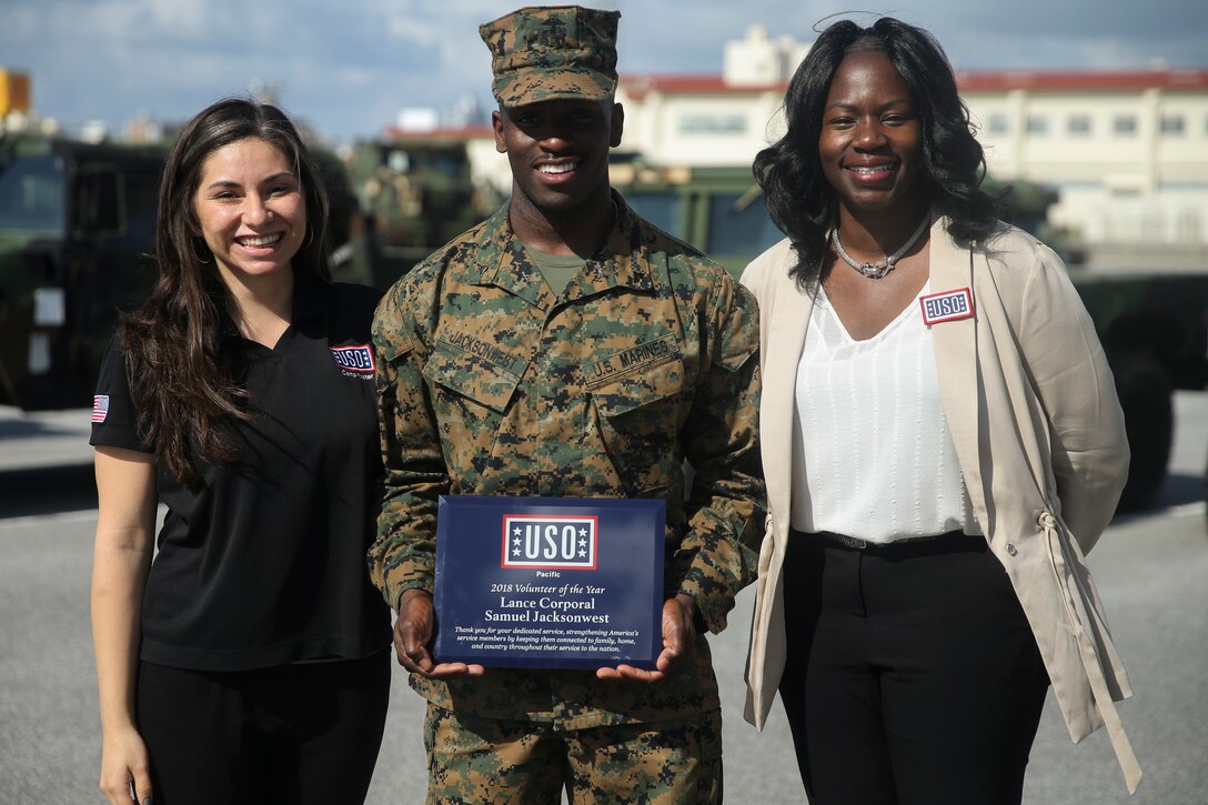 Lance Cpl. Samuel I. Jacksonwest, center, received the 2018 USO Pacific Volunteer of the Year award on Nov. 28, 2018 at Camp Foster, Okinawa, Japan. Jacksonwest received the award for his 480 volunteer hours at the Camp Foster USO. Jacksonwest was the winner among 1,400 volunteers in the Pacific region and the first active duty volunteer to receive this award in the last 4 years. Jacksonwest, a native of Atlanta, Georgia, is a network administrator with Headquarters Company, Combat Logistics Battalion 4, Combat Logistics Regiment 3, 3rd Marine Logistics Group. (U.S. Marine Corps photo by Lance Cpl. Armando Elizalde)