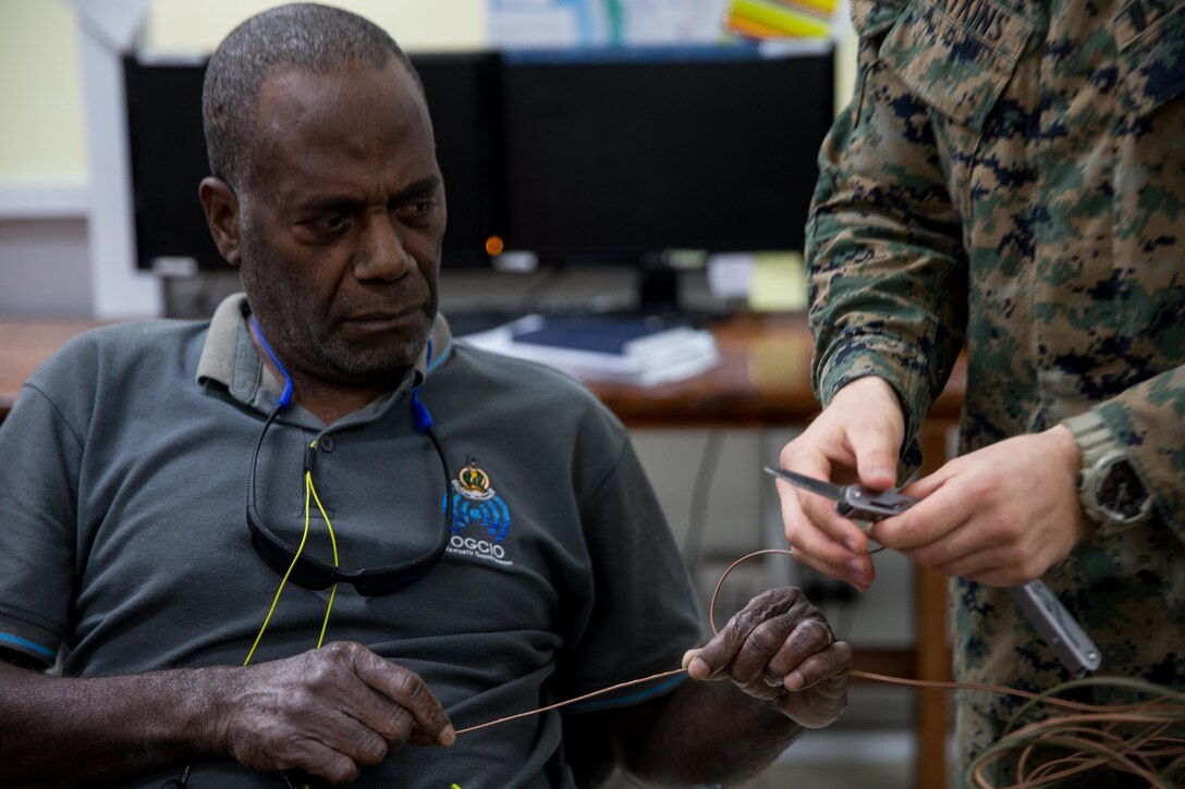 U.S. Marine Corps Sgt. Johnathan Watkins, right, a ground radio repairman with Task Force Koa Moana, shows a member of the Vanuatu National Disaster Management Office (NDMO) how to cut copper wire at Port Vila, Efate Island, Republic of Vanuatu, Nov. 14, 2018. The Task Force exchanged radio communication capabilities with NDMO in case of a humanitarian assistance and disaster and relief crises, as part of the Task Force’s continued multilateral engagements designed to strengthen and enhance relationships among the United States and partner nations in the Indo-Pacific and South Pacific regions. (U.S. Marine Corps photo by Staff Sgt. Gabriela Garcia)