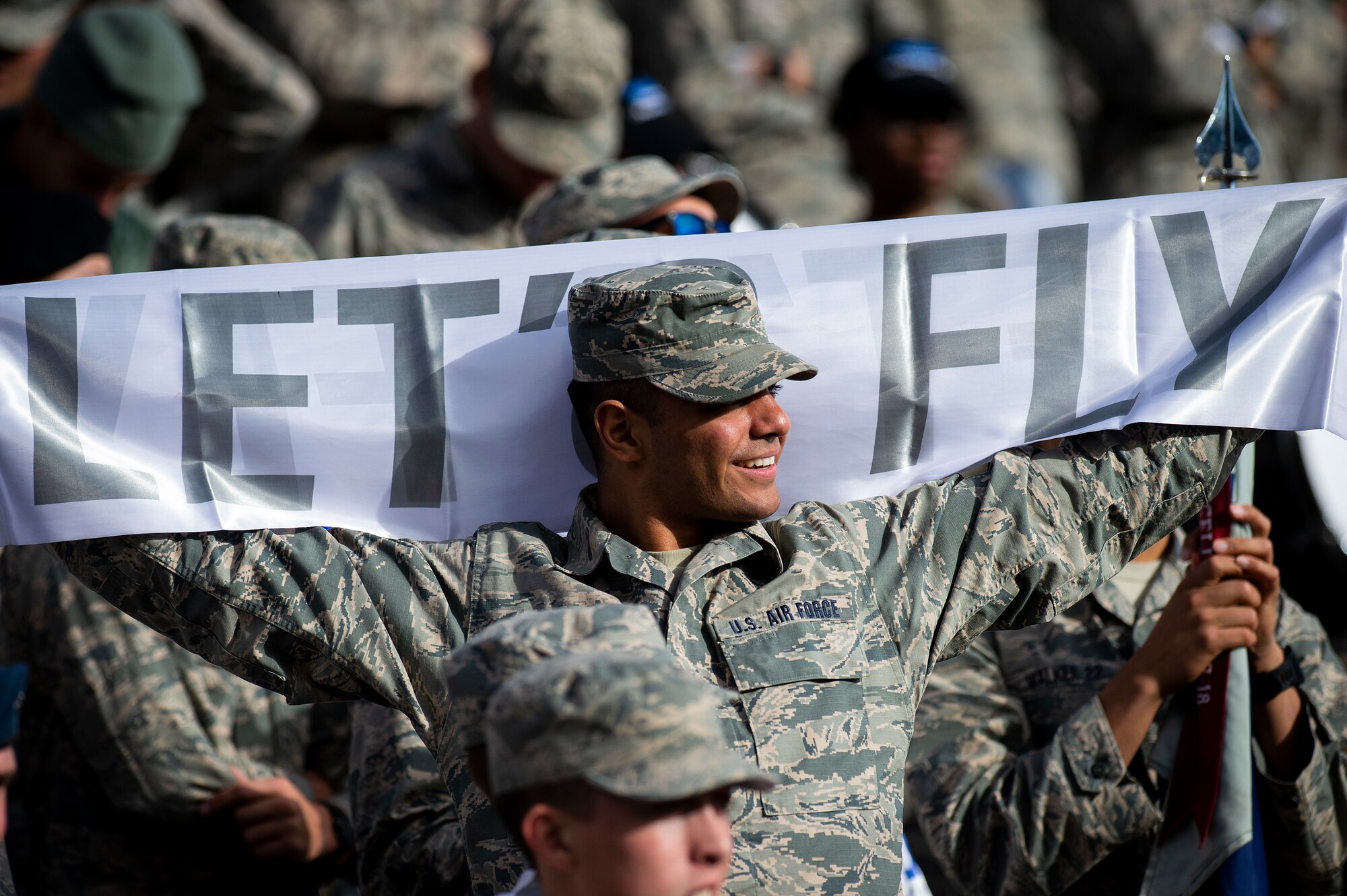 A cadet holds a banner that reads "let's fly"