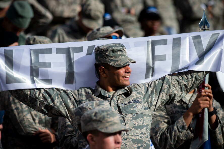 A cadet holds a banner that reads "let's fly"