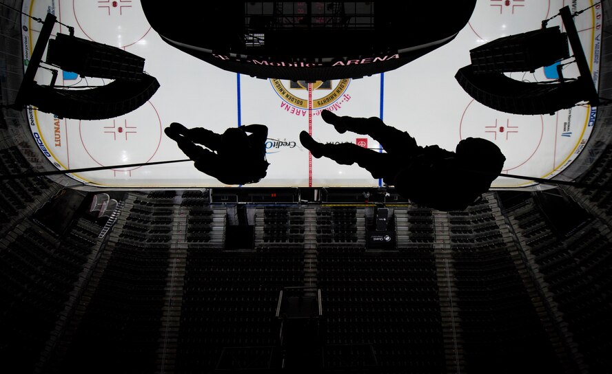 Two pararescuemen rappel over an arena