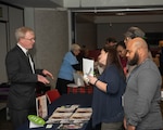 A gentlemen in a suit explains his charity to three associates.