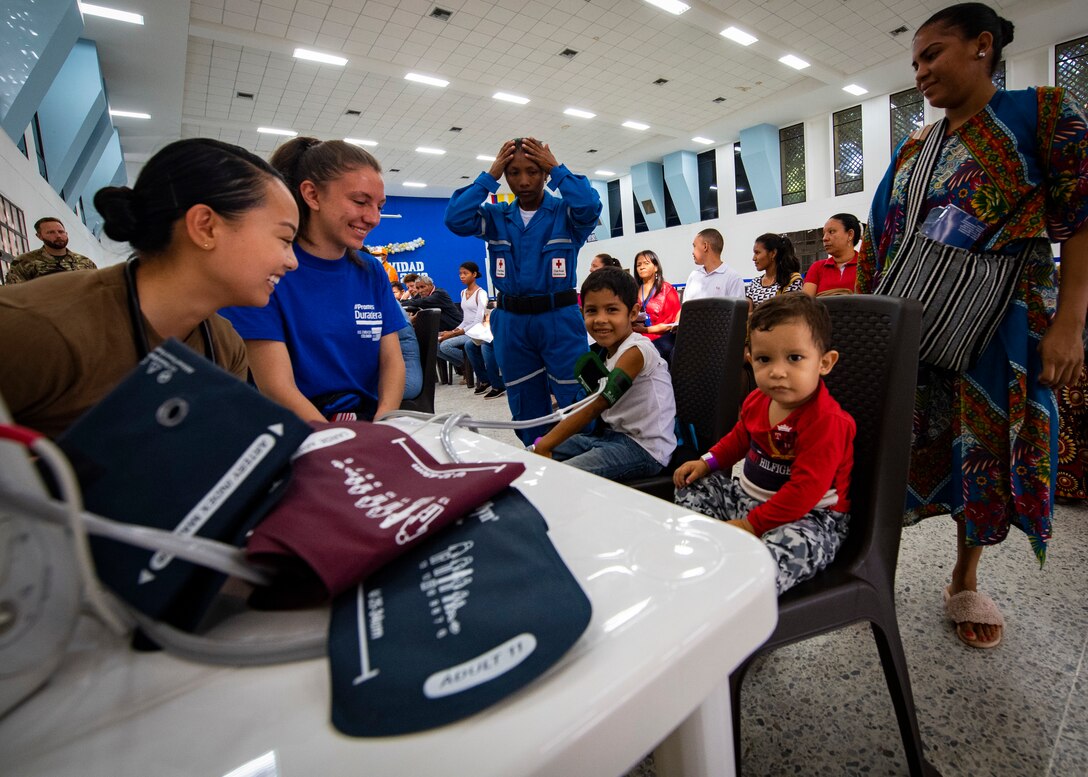 Ensign Adelin Guina (left), from Seattle, and Laura Osorio (center-left), a volunteer from the U.S. embassy in Colombia, check the vital signs of a young patient at one of two medical sites.