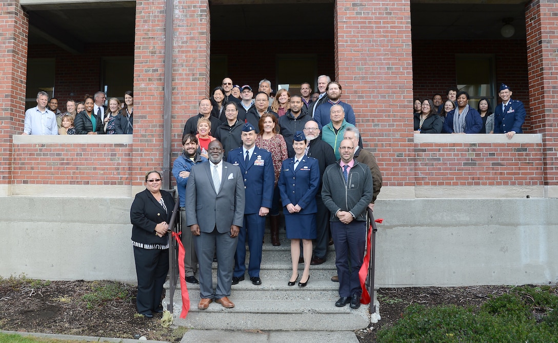 A large group of coworkers stand in front of their office building.