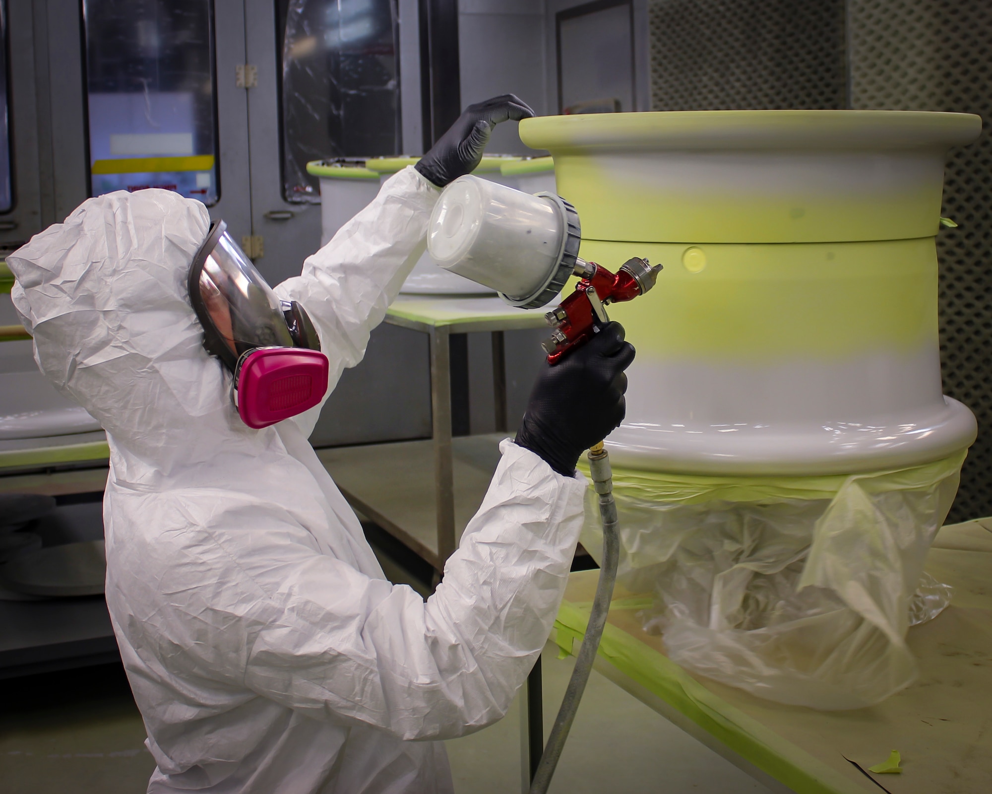 Airman 1st Class Alex Mceachin, 437th Maintenance Squadron sheet metal apprentice, utilizes a newly designed painting station to paint a wheel Nov. 30, 2018 at Joint Base Charleston, S.C. The new design elevates the wheel, exposing all the surfaces, on a stand with a lockable bearing apparatus to allow the wheel to spin, but remain secured. In its current design, three stands can be mounted on a moveable cart to allow mobility of the painted wheels to move them to the curing section of the shop.