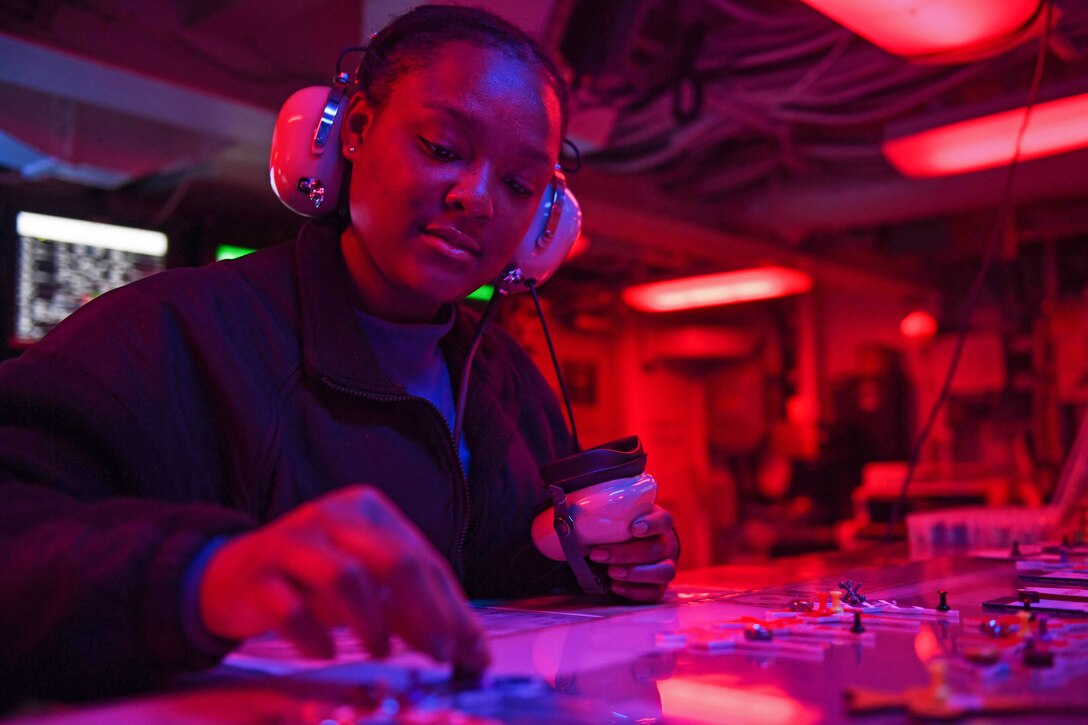 A sailor controls the switches on equipment.