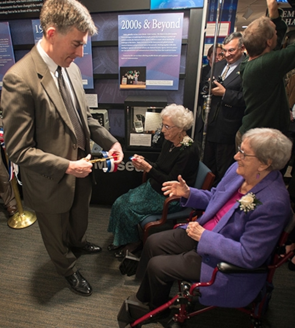 Photo of NSA Deputy Director John C. (Chris) Inglis hands a piece of the ribbon to Helen Nibouar (l) and Marion Johnson (r).