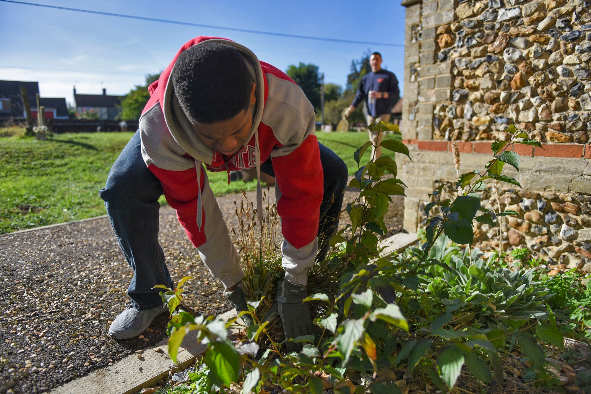 U.S. Air Force Staff Sgt. Kenneth Hummons, weeds along St. John’s Church during a volunteer event in Beck Row, England, Sept. 29, 2018. Approximately 20 individuals to volunteered to clean the church. (U.S. Air Force photo by Staff Sgt. Christine Groening)