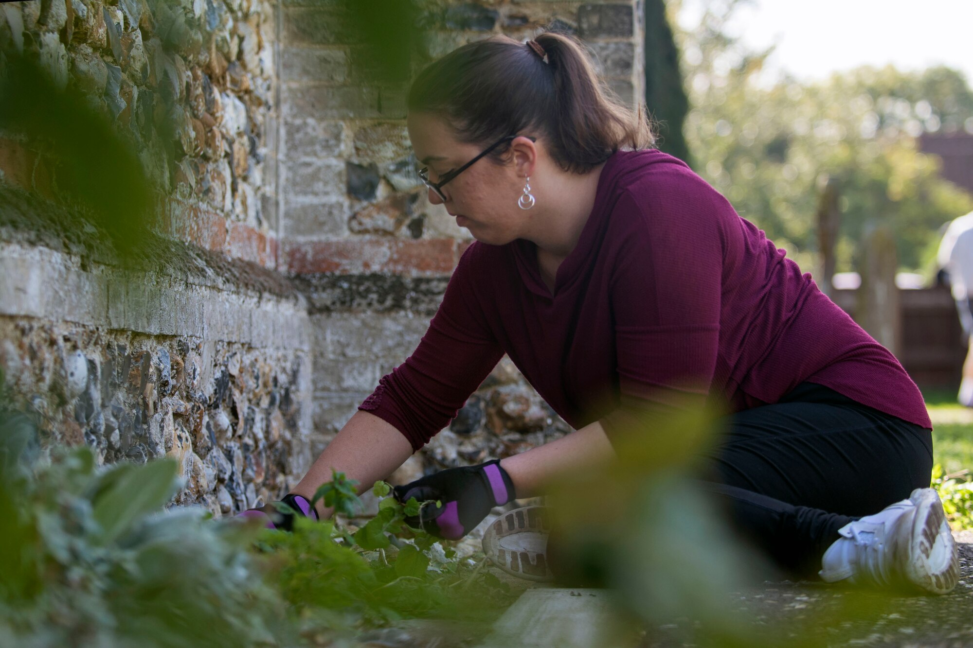 U.S. Air Force Tech. Sgt. Holly Lodin, weeds along St. John’s Church during a volunteer event in Beck Row, England, Sept. 29, 2018. Volunteers from the 48th Fighter Wing and Team Mildenhall painted, pulled weeds and cleaned the grounds of the church. (U.S. Air Force photo by Staff Sgt. Christine Groening)