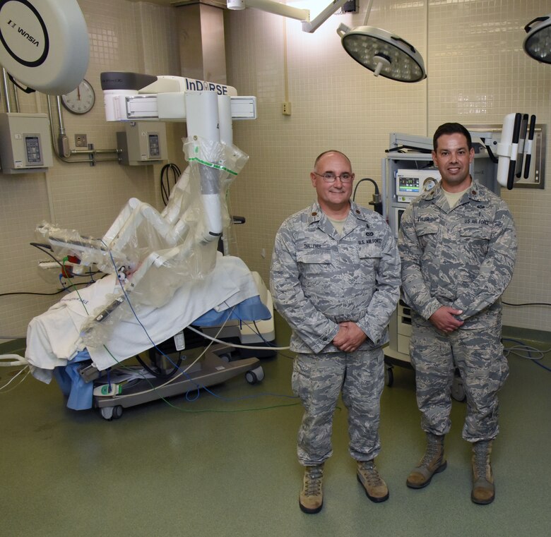 U.S. Air Force Maj. Joshua Tyler, 81st Surgical Operations Squadron Institute for Defense Robotic Surgical Education program director, Keesler Air Force Base, Miss., and Maj. Scott Thallemer, InDoRSE program coordinator, pose for a photo inside the robotics surgery training room at the clinical research lab on Keesler Air Force Base, Mississippi, Sept. 13, 2018. (U.S. Air Force photo illustration by Kemberly Groue)