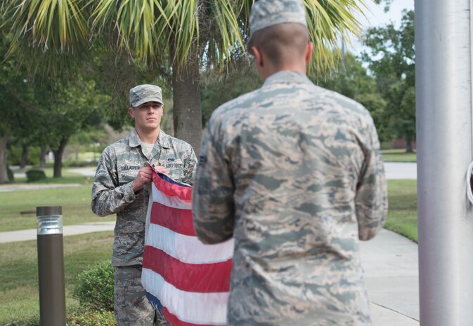 Airman 1st Class Joshua Gallagher, 437th Aerial Port Squadron air transportation journeyman, and Senior Airman Benjamin Diamond, 437th Aircraft Maintenance Squadron aerospace maintenance journeyman, fold the American flag during a retreat ceremony Sept. 28, 2018, at Joint Base Charleston, S.C.