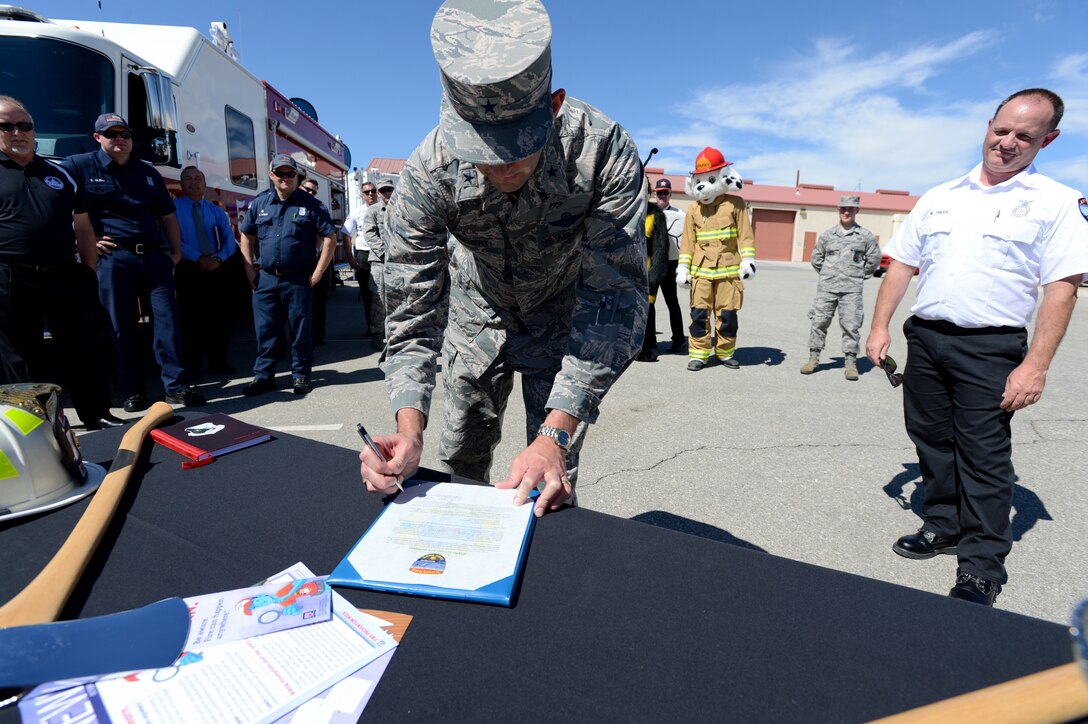 Brig. Gen. E. John Teichert III, 412th Test Wing commander, signs this year’s Fire Prevention Week Proclamation as Mike Pinan, Edwards AFB Fire Prevention assistant chief (right) watches, Sept. 25. The general signed the proclamation while visiting with the 812th Civil Engineer Squadron. (U.S. Air Force photo by John Perry)