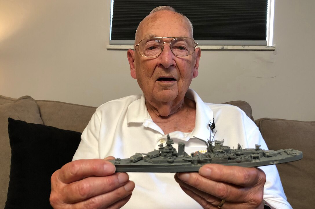 A man hold a toy battleship.