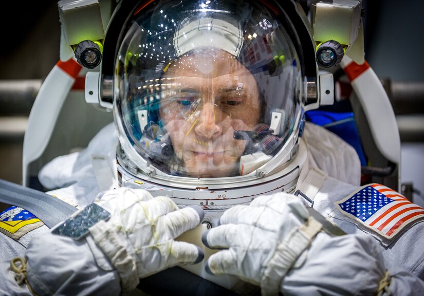 Air Force Col. Nick Hague wears a spacesuit as he awaits more training. The facility’s lights reflect in his helmet’s visor.