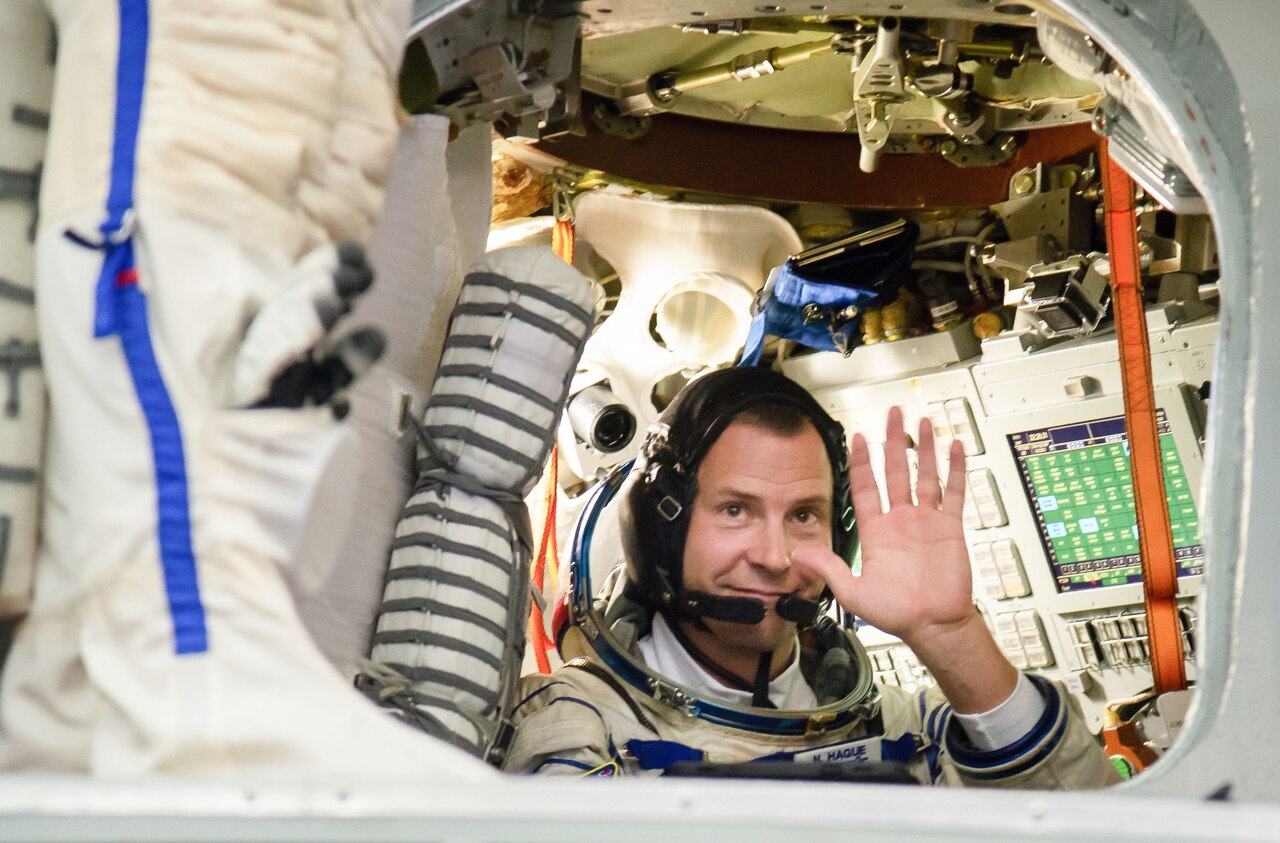 Air Force Col. Nick Hague, a NASA astronaut, waves from inside a Soyuz simulator.